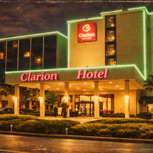 The image shows a Clarion Hotel building at night with neon lights, palm trees, and a lit entrance.