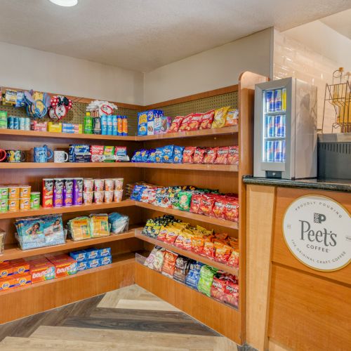 The image shows a small snack and drink display with various packaged goods on shelves and a Peet's Coffee station.