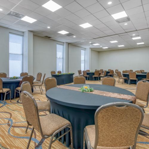 An empty conference room with round tables and chairs arranged neatly, creating a layout for a meeting or event setup.