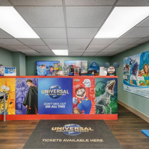 This image shows the interior of a Universal theme park ticket office with colorful posters and a counter displaying promotional materials.
